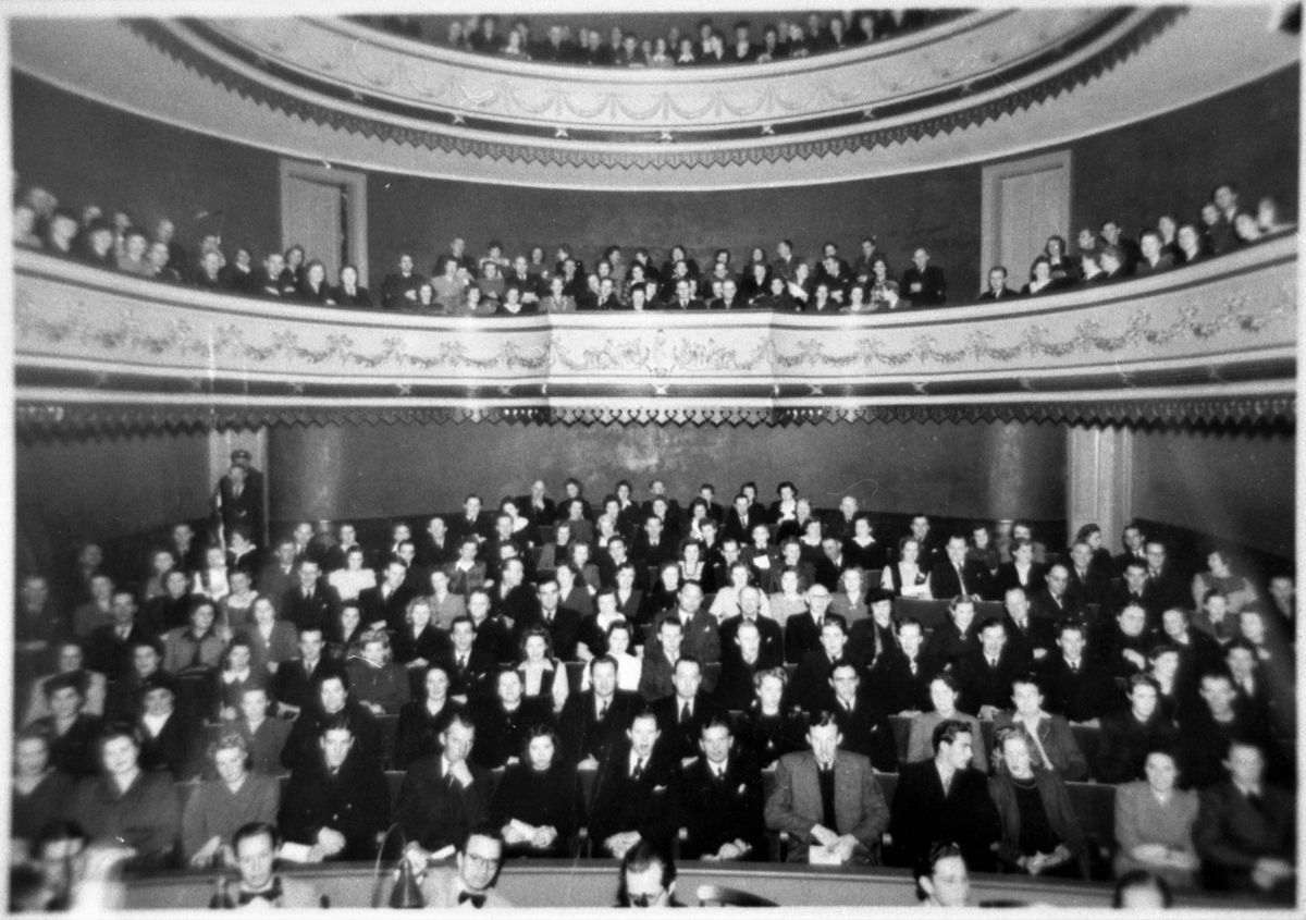 Varbergs teaters salong med publik, taget från scenen. I nederkanten syns några ansikten på musikerna i orkesterdiket.