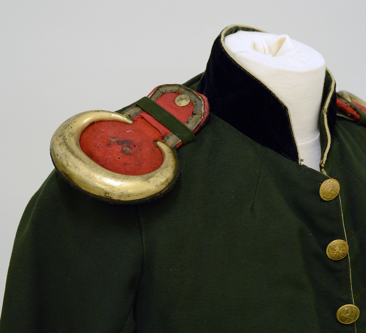 Uniformsjakke. Med epauletter for Skiens borgerkorps. Olivengrøn, røde epauletter med messingkanter og messingknapper. Fra protokoll.