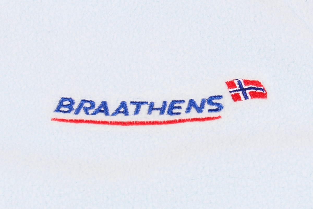 Lys blå genser med rund hals. Braathens-logo på brystet og logo til Norges fotballforbund på høyre erme, samt påskrift på ryggen. Størrelse L.