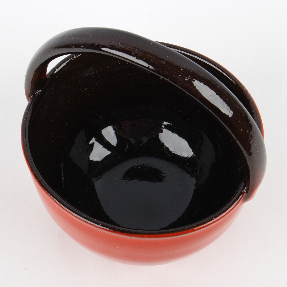 Uranrød skål med hank med sort glasurkant.