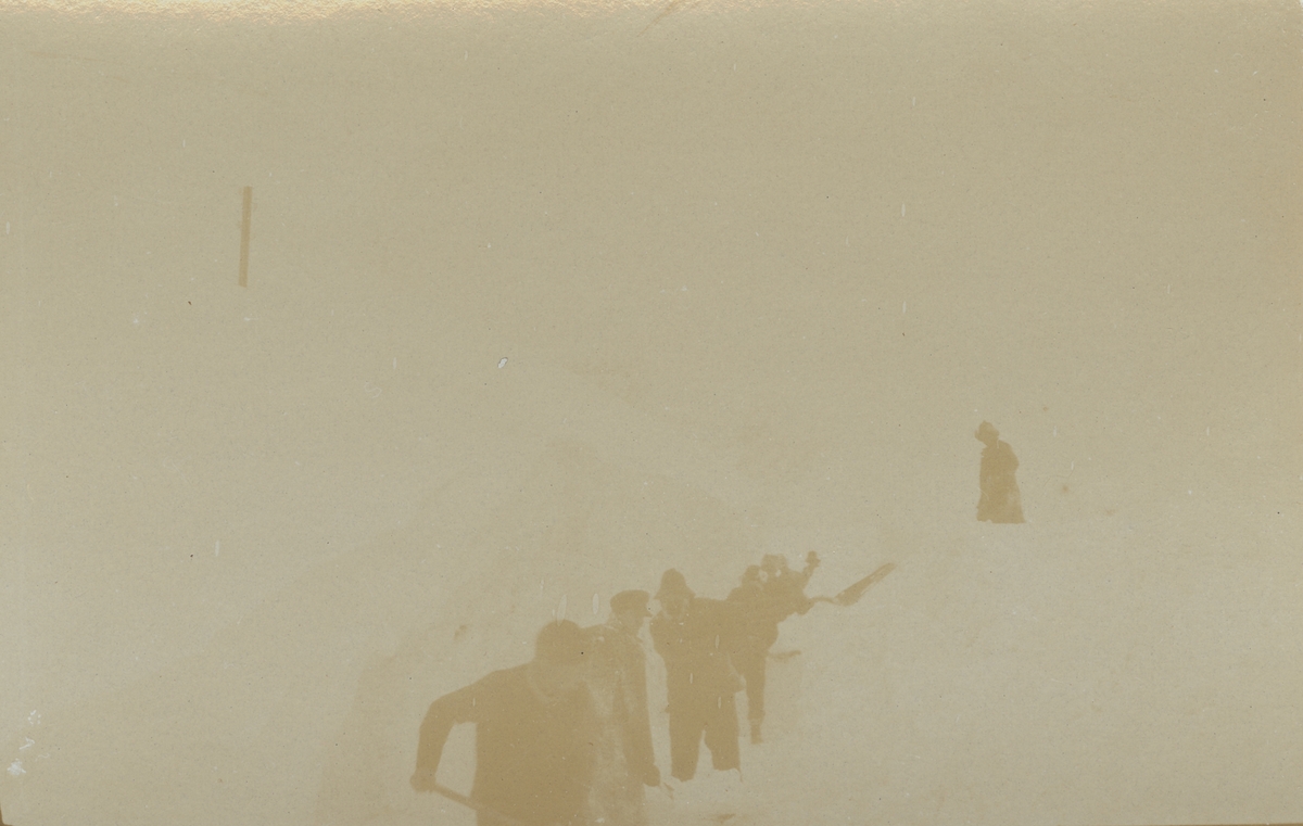 Fotografi från expedition till Spetsbergen. Motiv av en grupp män som gräver ett dike i ett snölandskap.