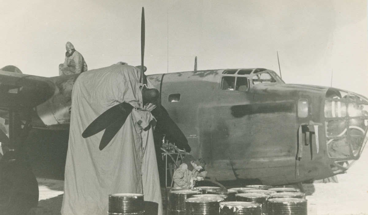 Fotografi från låda märkt Bernt Balchen. Balchen var norsk-amerikansk flygare, polarforskare och militär. Motiv av två män vid flygplan och bränsletunnor. Flygplanet är eventuellt en Consolidated B-24 Liberator.