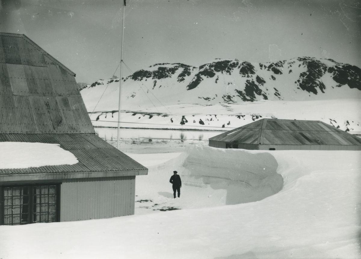 Bild från expedition i Antarktisområdet. Motiv av man vid insnöade hus.