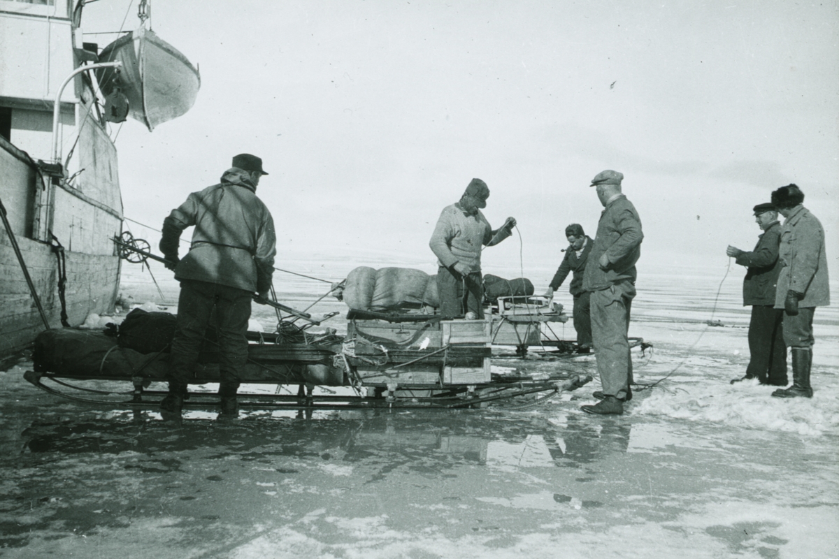 Glasnegativ med motiv av sex män med slädar invid fartyg på is.