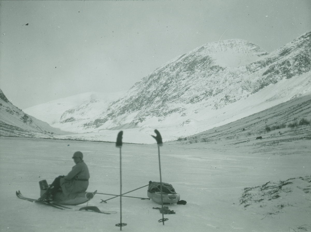 Fotografi från expedition till Spetsbergen. Motiv av kvinna med packning i snötäckt bergslandskap.
