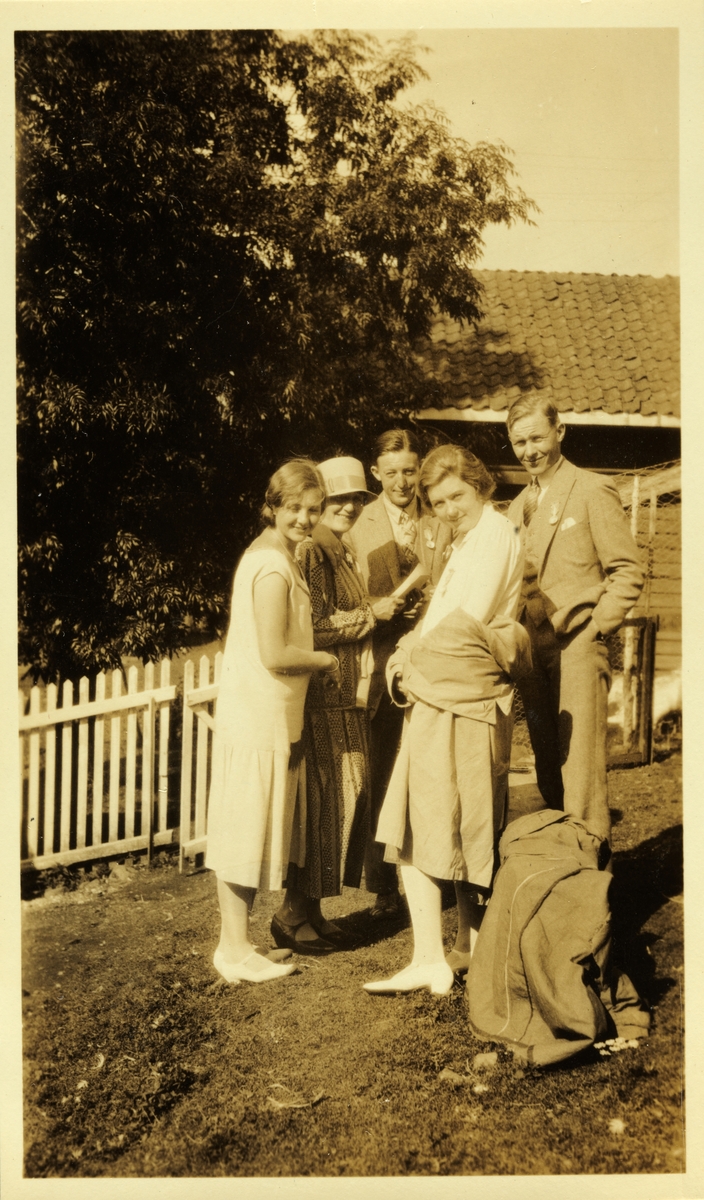 Tre kvinner og to menn fotografert utenfor stakitt, muligens på Opperud gård på Ringerike. Kvinnene er  Sisken Skjelderup, ukjent og Cecilie Broch. Antagelig fotografert sommeren 1926. 