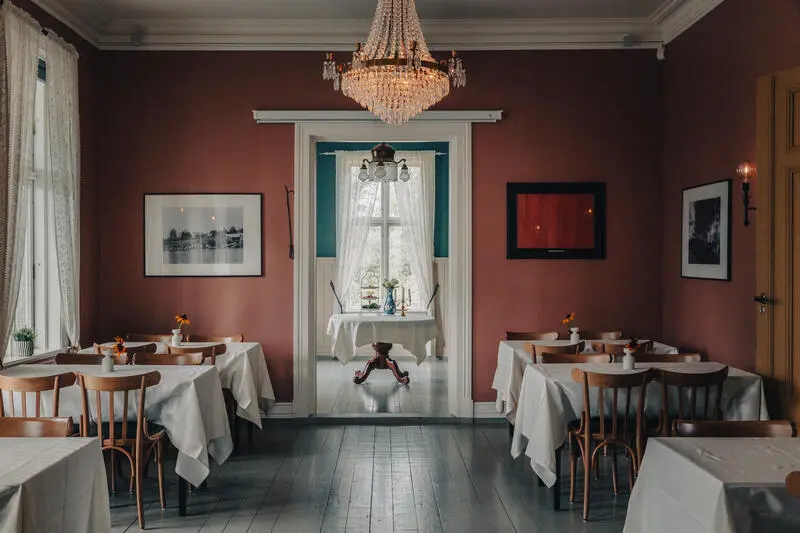 Historiske lokale med lysekrone og dekte bord.