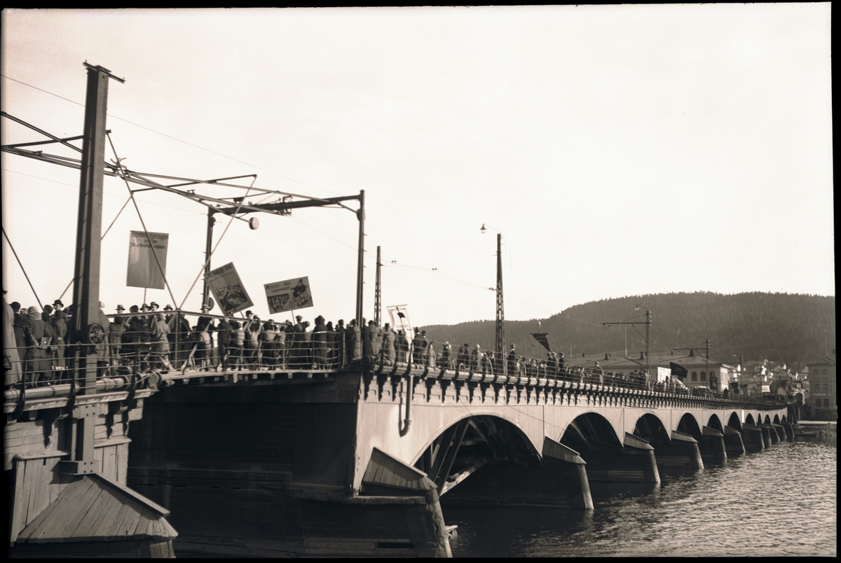 1. maitog over den gamle bybrua i Drammen. I bakgrunnen skimes ...