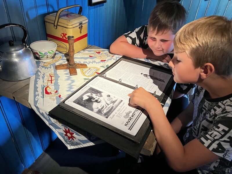 Bildet viser to barn som studerer et album med bilder og tekst.