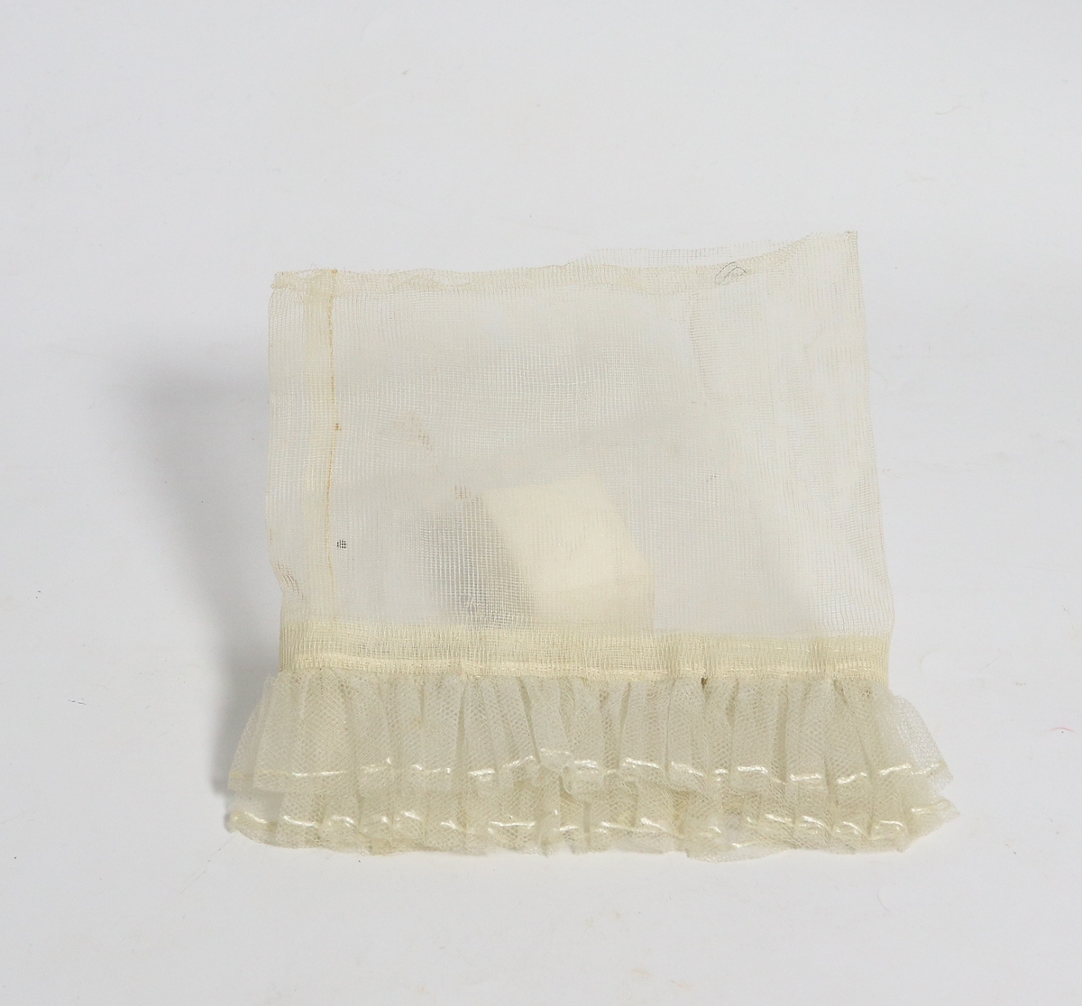 Hvit gjennomsiktig brudeutsyr av silke betsående av brudeslør, myrtekrans og kjolepynt.