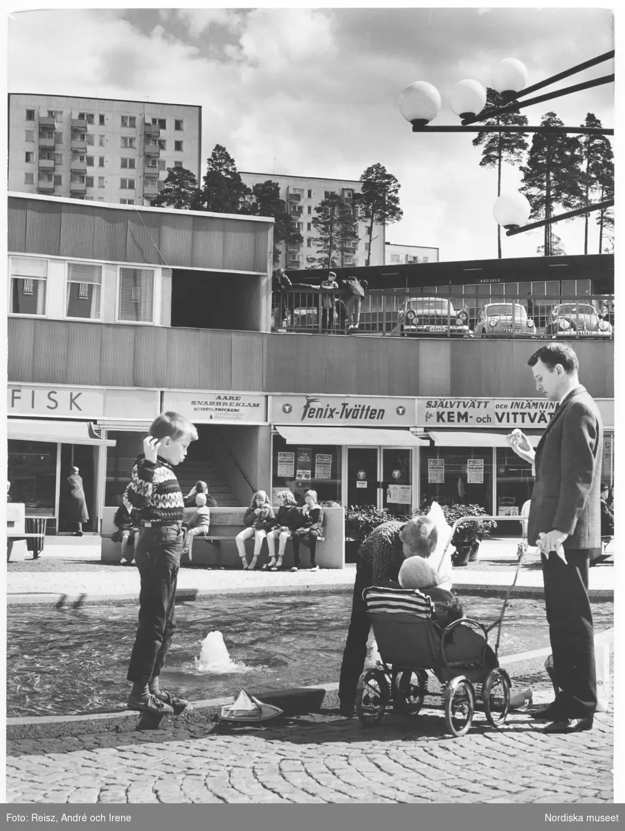 Stockholm. Rågsveds centrum. I förgrunden vid fontänen, en man med tre barn, varav ett i barnvagn.