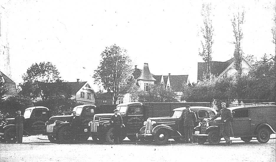 Vognmann Svendsen oppstilt med sine biler ved jernbanestasjonen