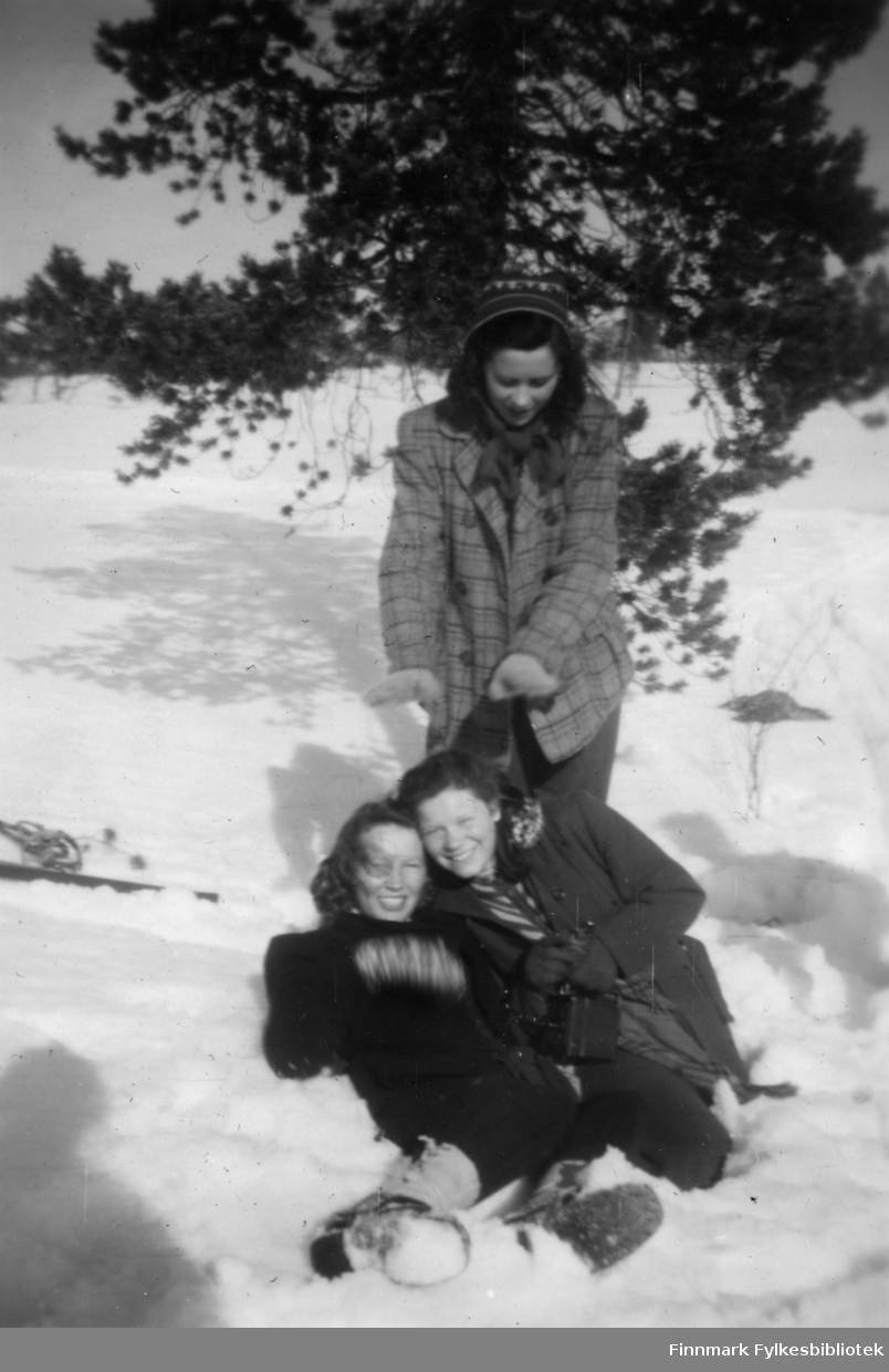 Tre kvinner leker seg i snøen. Nærmest ligger Bodil Pedersen. Anne Høier står bak Kitty Stune. Til venstre ligger det ski