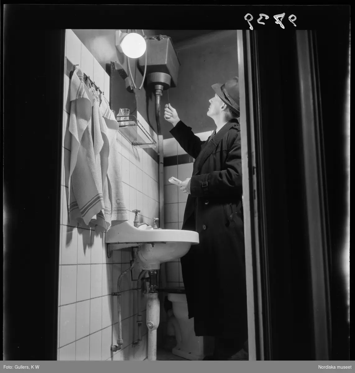 507 E Ultuna Fjäderfälaboratorium. En man inspekterar ett toalett-utrymme.