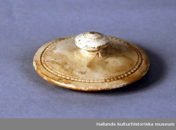 Kaffekanna av benvitt porslin. Oval med svängd, räfflad pip. Fot och lock ornerade med pärlränder i relief.