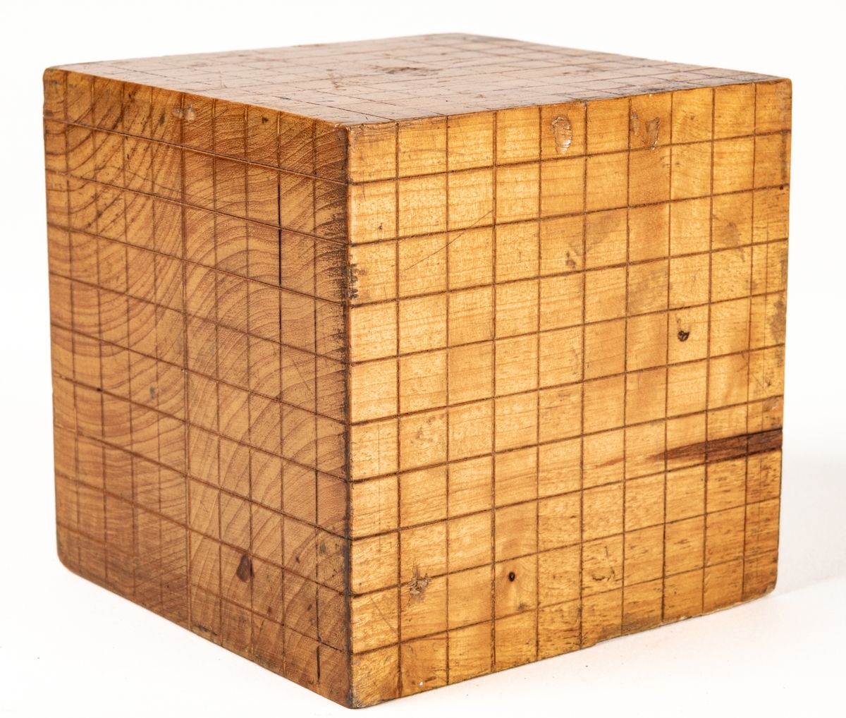 Illustrationsmodell i matematik. Två kuber av lövträ visande dm³ uppdelat i cm. En kub är delad i tio lösa skivor och förvaras i plåtlåda. Den fjärde är likaså delad i skivor men den tionde dessutom i stavar.