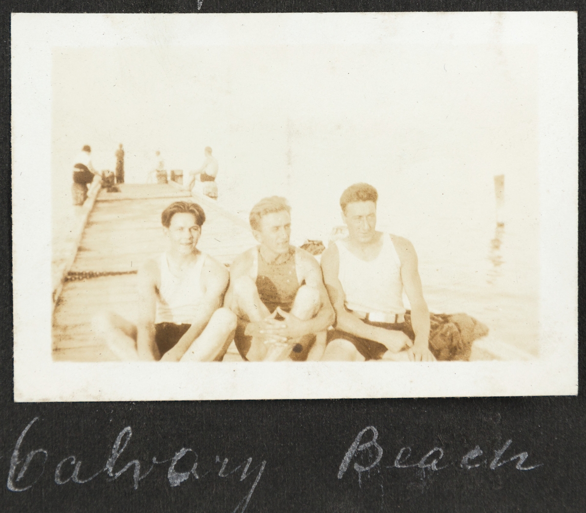 Tre unge menn smiler til fotografen på ei brygge på Calvary beach. Fra høyre er Bjarne Fixdal og Kalle (Karl Bårdsen).
