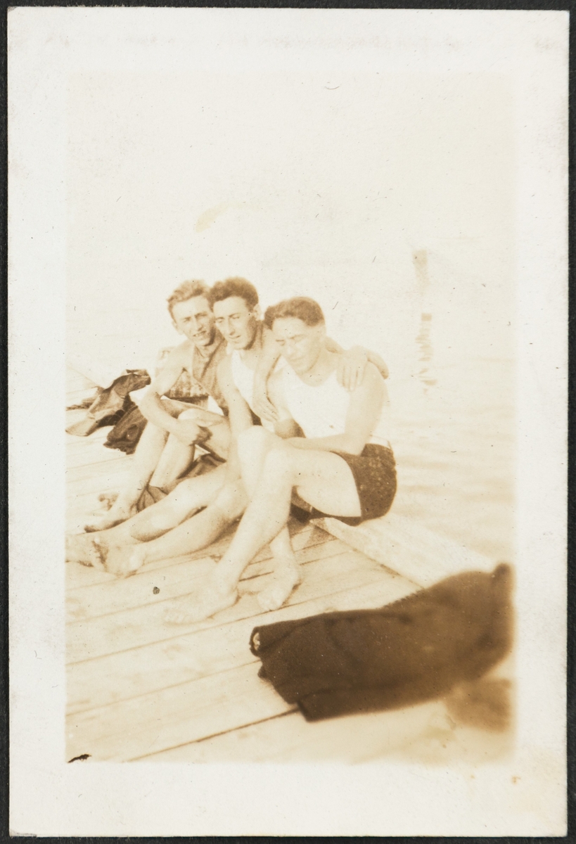 Tre unge menn smiler til fotografen på ei brygge på Calvary beach. Fra venstre er Kalle (Karl Bårdsen), Bjarne Fixdal og antageligvis Jacob Lura.