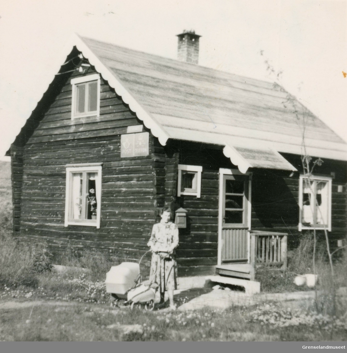 Poståpneriet på Elvenes i Sør-Varanger, her fra 1953. 
Poståpner Jenny Thomassen står utenfor huset som både fungerte som bolig og poståpneri. 
I barnevogna ligger den nyfødte datteren Bente Thomassen. 
