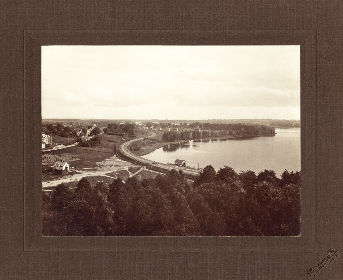 Utsikt från domkyrkotornet mot sydost, ca 1912. Man ser Växjösjön och en del av Öster.
I fjärran skymtar S:t Sigfrids sjukhus och Teleborgs slott.