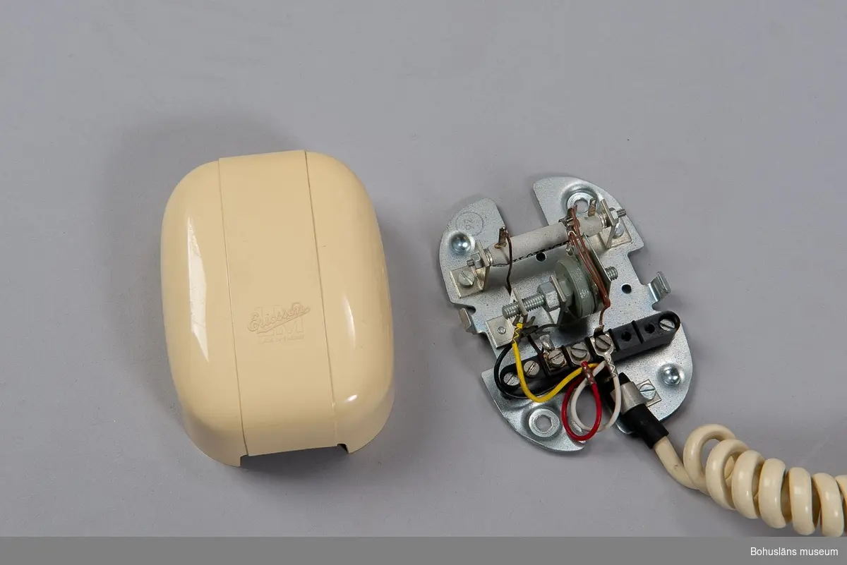 Telefonapparat Ericofon, även kallad Kobra, för AT-system, huvudapparat (med ringklocka), anknytningsapparat till växel (med ringklocka) och sidoapparat (utan ringklocka). Bordsmodell, m57, av grå termoplast utan inbyggd ringklocka och med alla komponenter sammansatta till en enhet. När telefonen används som huvud- eller anknytningsapparat ansluts en separat väggmonterad avstängningsbar ringklocka. Fingerskivan av plast är försänkt i apparatfoten. Klykfunktionen är realiserad med en knapp som skjuter ut ur fingerskivans centrum och påverkas av apparatens tyngd.