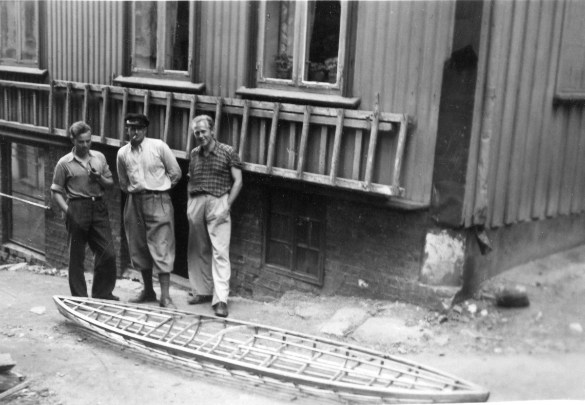 Sverre Gofjeld bygger kajakk. Tre karer ser på. Bjarne Eskeland , til ventre. 1950-tallet.