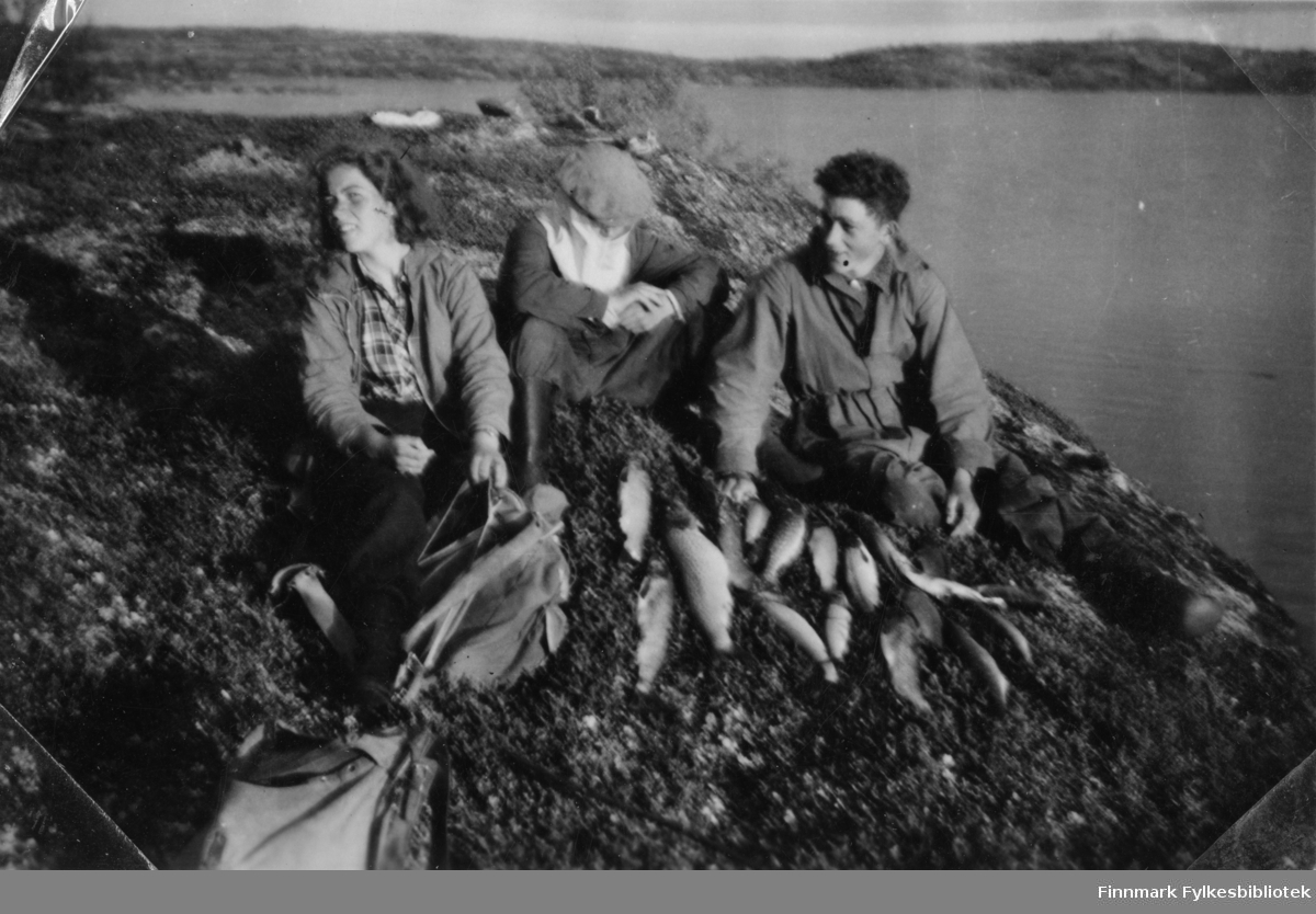 Søsken Jenny Gabrielsen (gift senere Drannem) til venstre og Olav Gabrielsen til høyre. Person i midten ukjent. De er på fisketur i et sted i Sør-Varanger.
