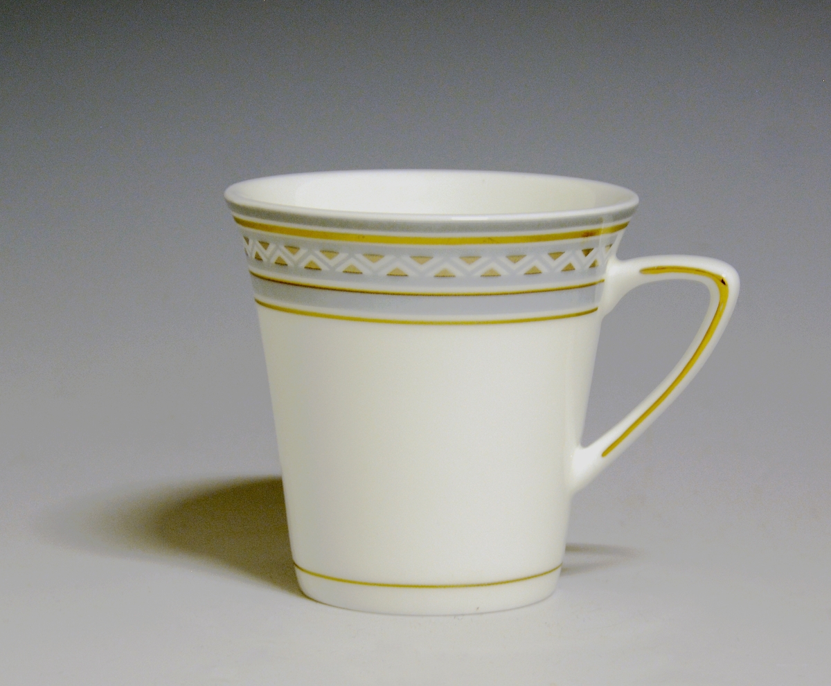 Kaffekopp av porselen med hvit glasur. Dekorert med bord øverst i blågrått og gull. Gullstrek over nedre kant og på hanken.