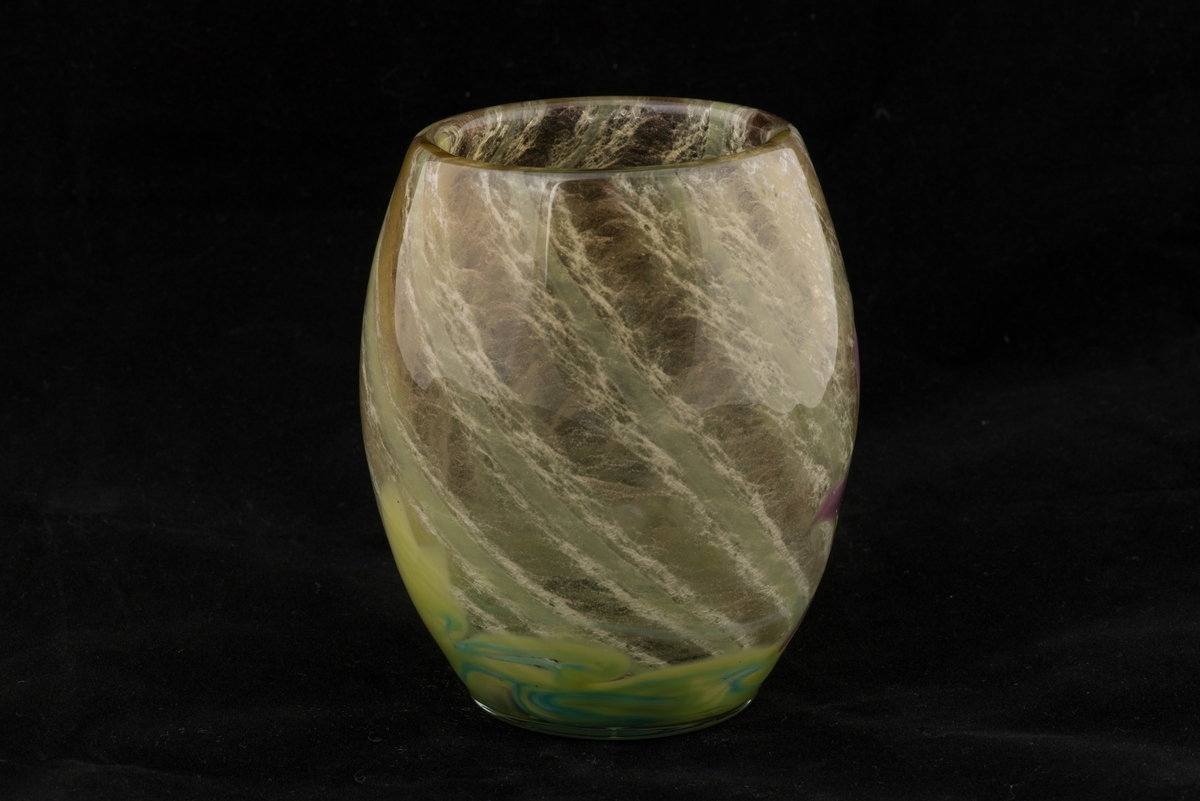 Välsad glasvas i jugendstil.
Svagt bukig vas med växtmotiv. Invälsad spiralvriden flockig glasmassa i vitt, gröngult, grönblått och mörkblått. Påklippt och invälsad blomma i form av en violett akleja samt ett grönt blad.