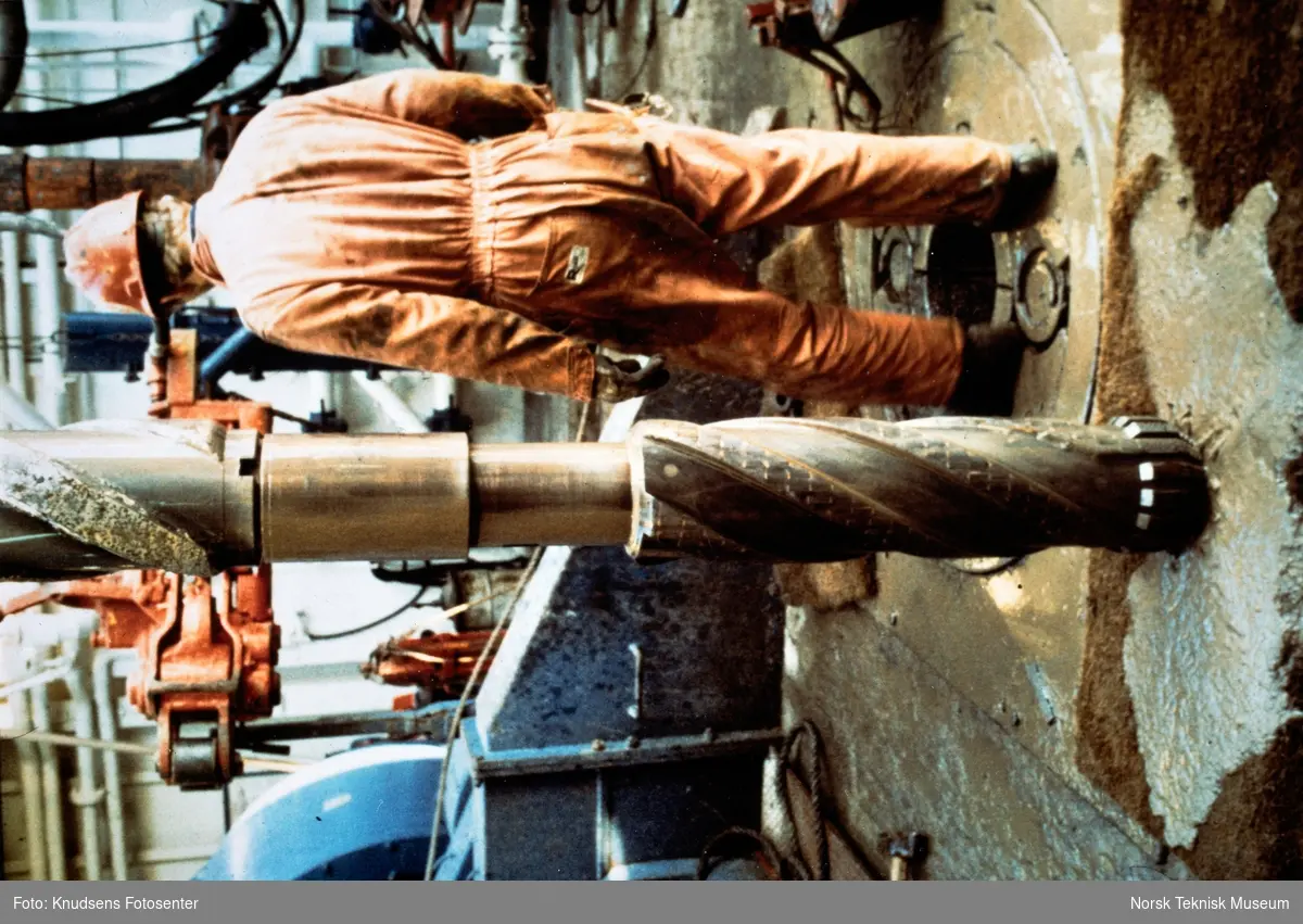 En oljearbeider står ved et borr på en oljeplattform.
