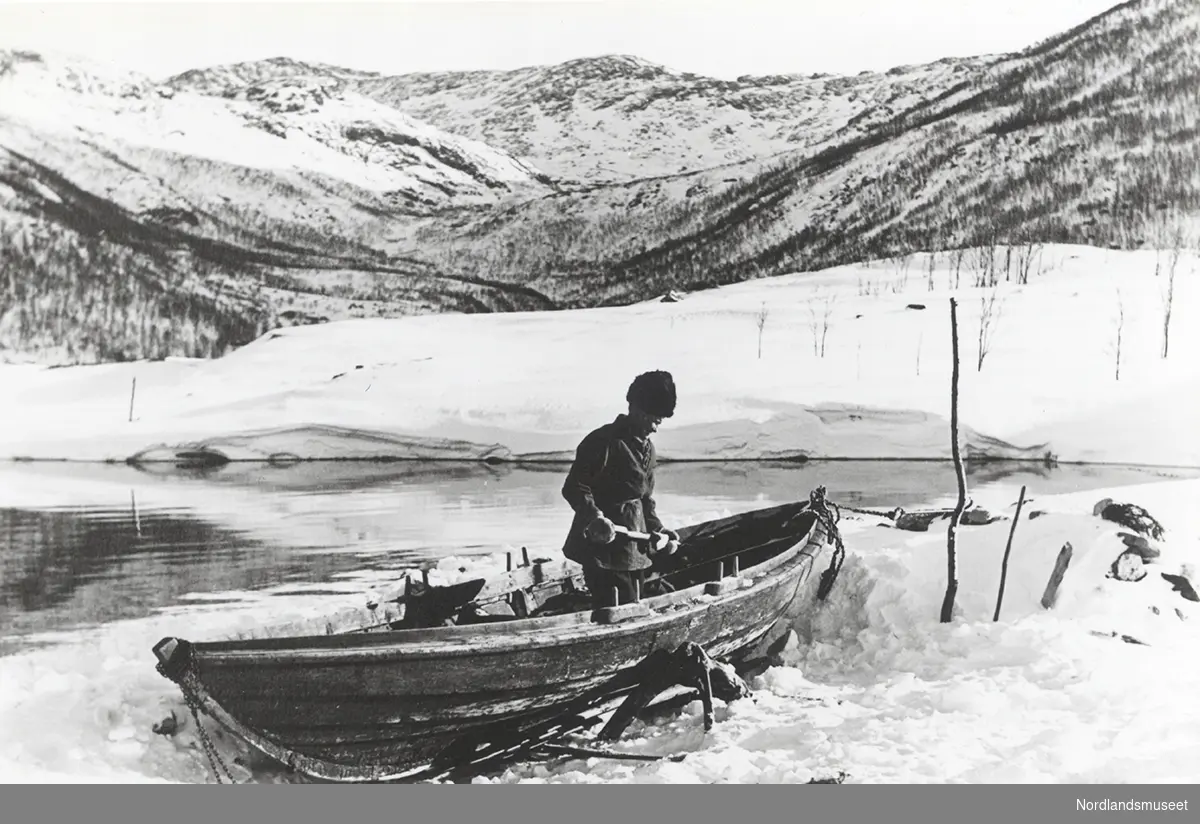 Petter Nilsen Kuljok måker båten, som ligger på land ved Langnes i Sørfjorden. 