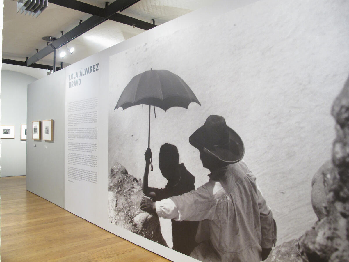 Dokumentasjonsfoto fra utstillingen Lola Álvarez Bravo. Bildet forestiller en mann og en kvinne som står på en høyde ved sjøen. Mannen holder en parasoll over hodet på kvinnen.