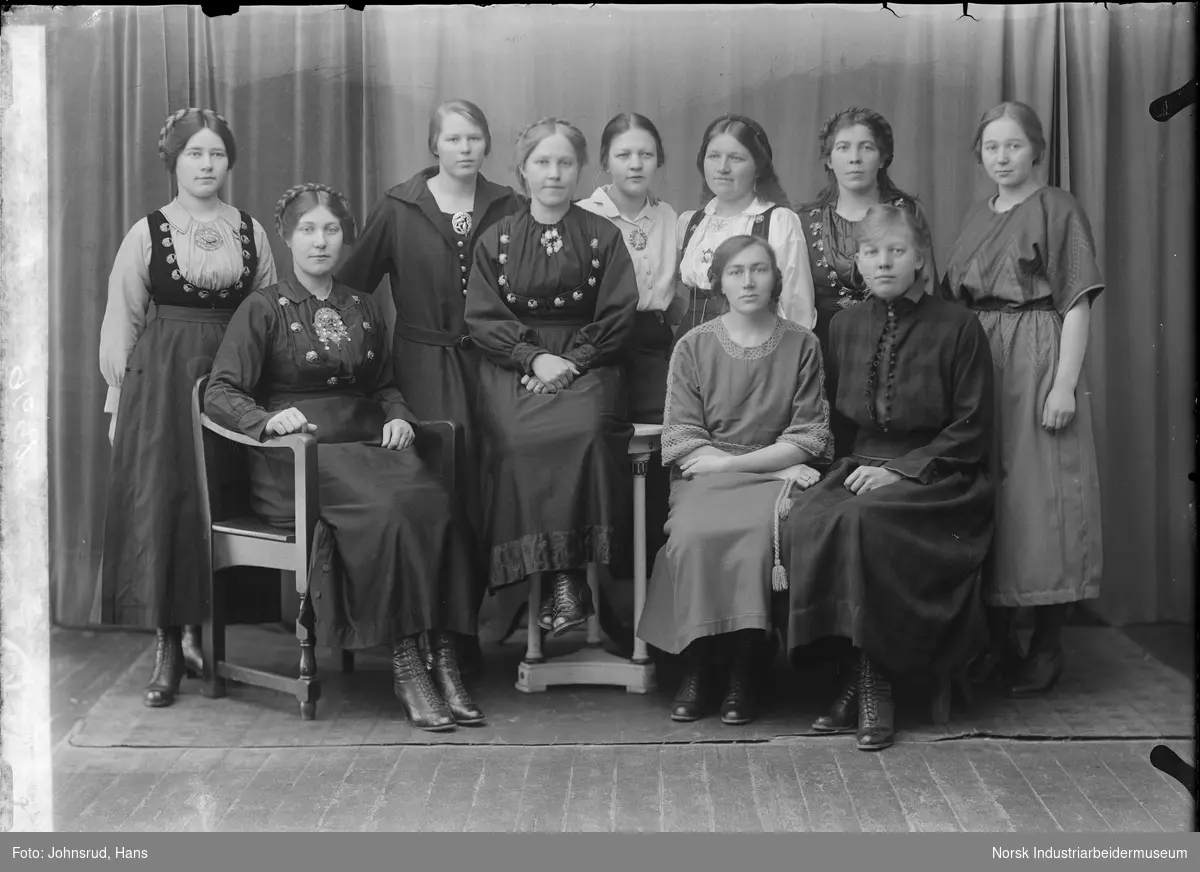 Gruppeportrett. Kvinner fra Vevskolen på Heddal. Alle kledd i pentøy, noen i kjole og andre i stakk.