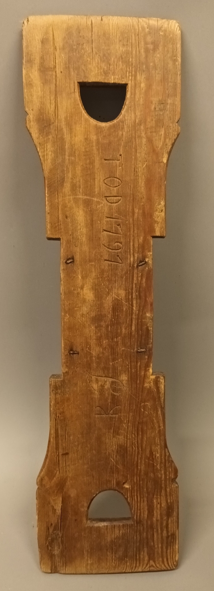 Linhekle laga av ei treplate med handtak i eine enden. På treplata er det sett på ein kloss med mange spisse jernpiggar.
Bak på linhekla er det skore inn bokstavane TOD og KJ og årstalet 1797.