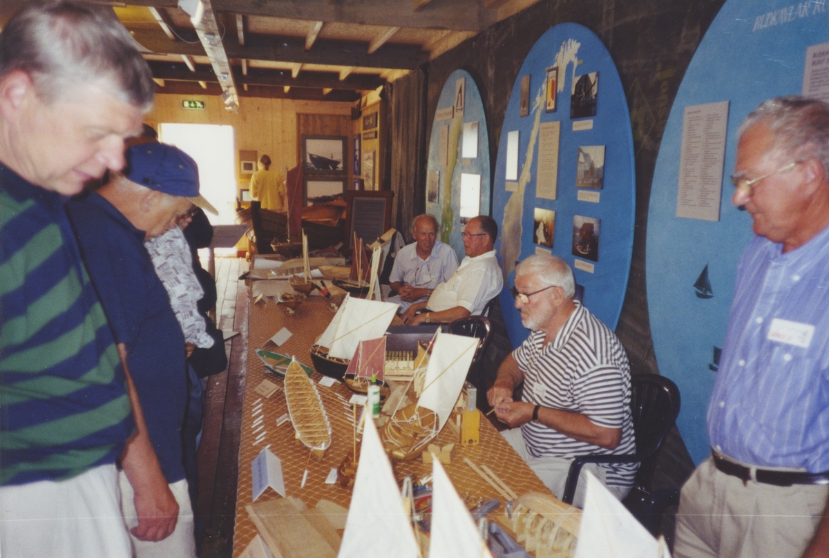 Utställningen "Människor och båtar i Norden" på fartyget M/S NORDWEST. Herrar visar fartygsmodeller för besökare.