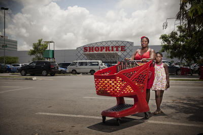 Mor og barn med en rød handlekurv utenfor et shoppingsenter i Luanda, Angola.