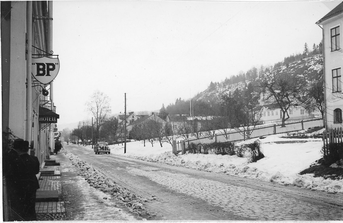 Brahegatan i Gränna en vinterdag med snöslask i vägkanten. Hotell Brahe till höger med skyltar för "BP". "Vättermuseet" upp till höger. En bil står parkerad lite längre bort på gatan.