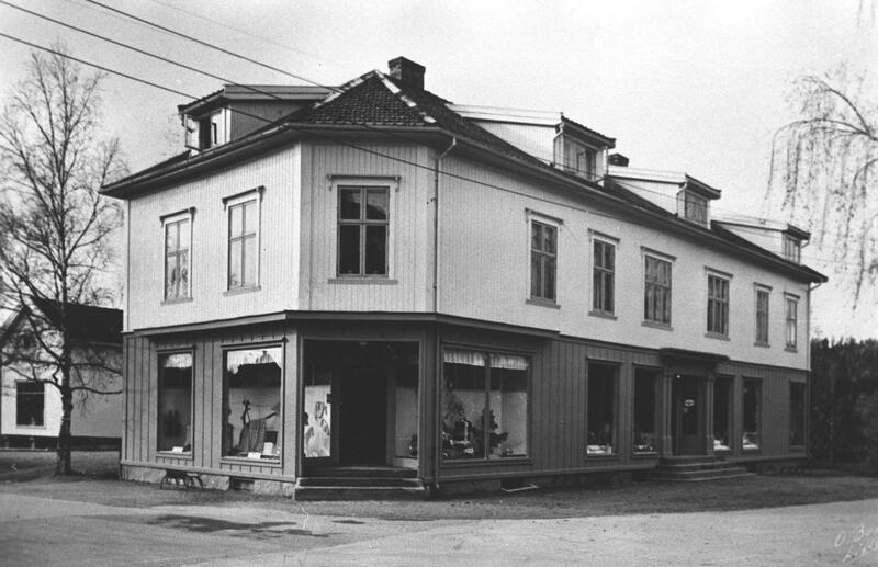 Aasheim bygningen ble utvidet på den siden som lå ut mot Stasjonsveien. 1. etasjen ble delt i en manufakturforretning på hjørnet og landhandelen på langsiden. Bak huset skimtes en bakbygning, som ble brukt som lager for byggevarer. Foto: Odd Barkald, MiA.