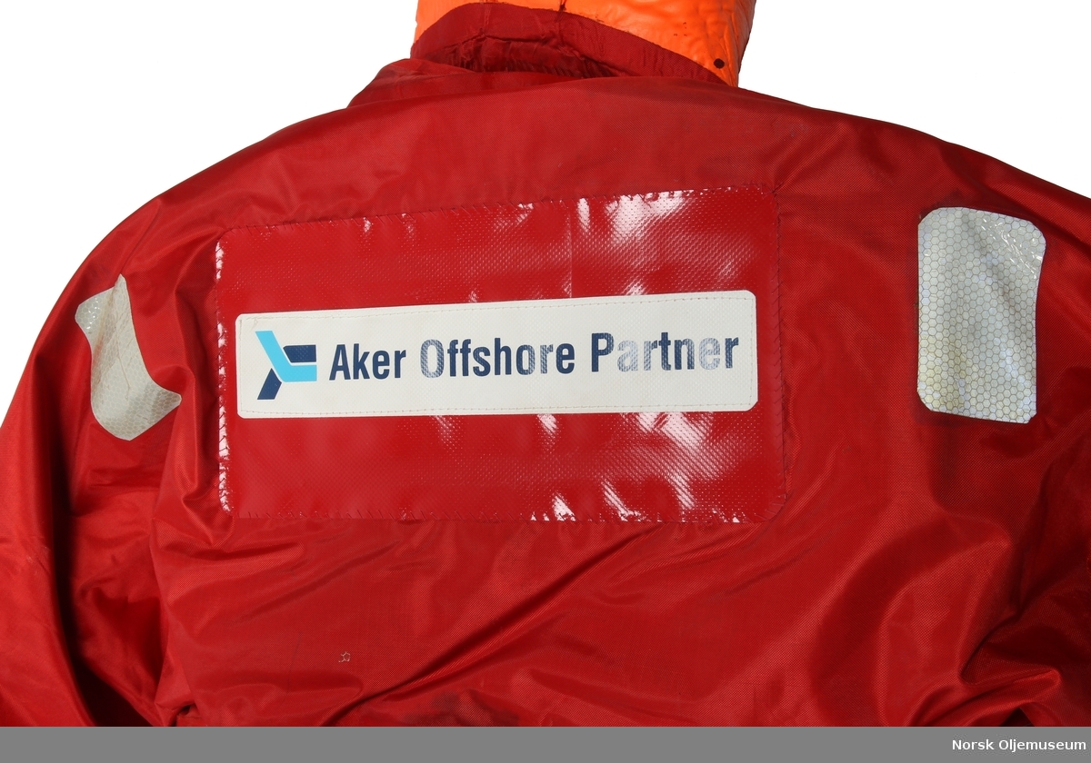 Redningsdrakt med Aker Offshore Partner sin logo på ryggen. 

Drakten er produsert av en flammebestandig neopren-nylonduk og er utstyrt med fluorescerende ytterhette med påsydde reflekser. Den har løst innerfôr som er festet til drakten med borrelås. Faste flytemidler er plassert i lommer i fôret.