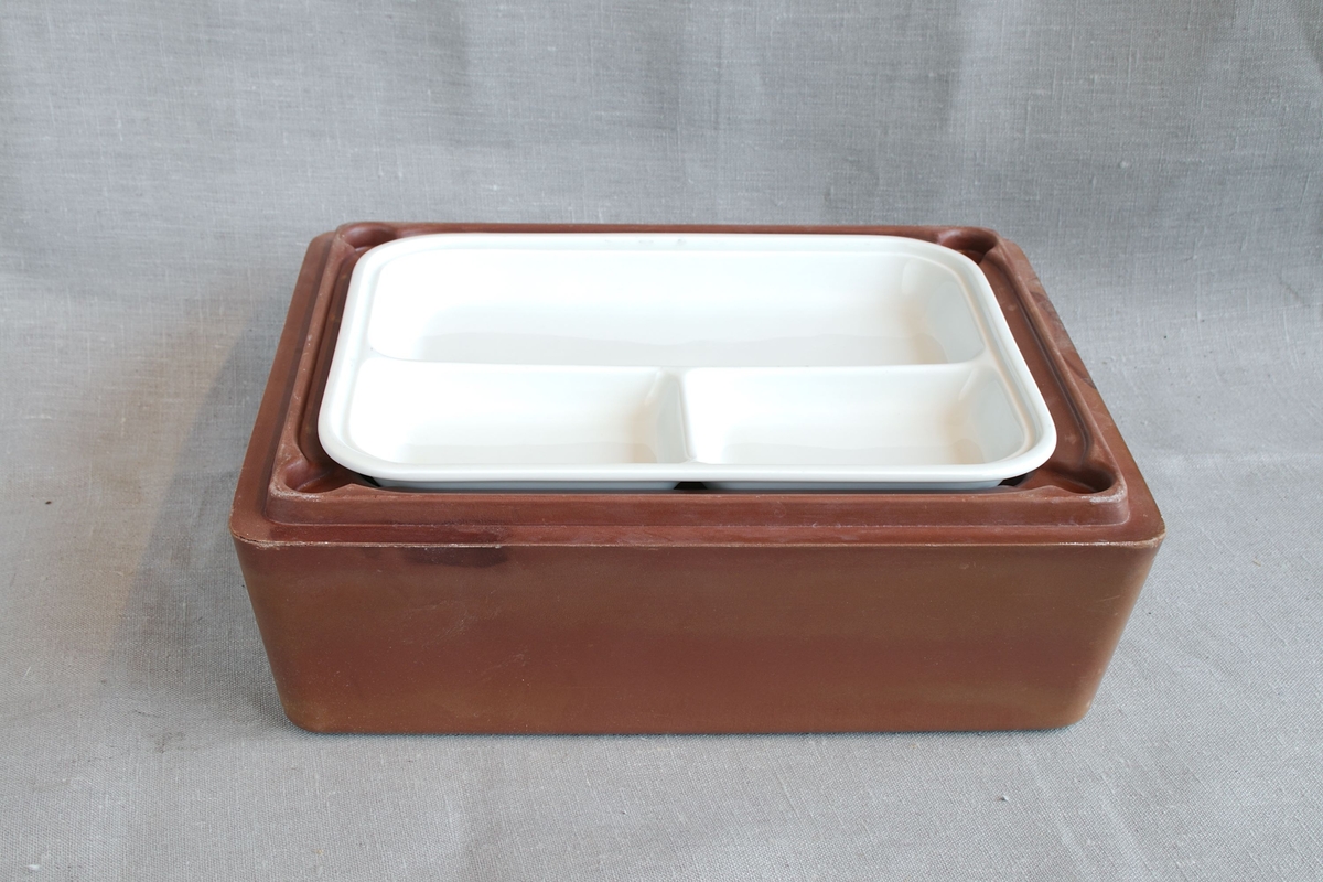 Rektangulær matboks i brun plast. Boksen har lokk, og inneholder servise for matservering.