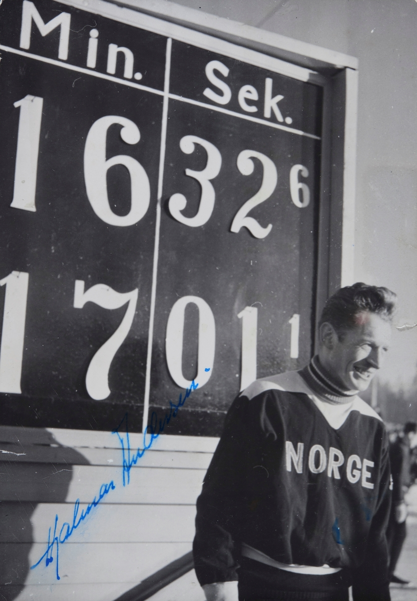 Hamar stadion, skøyteløper Hjalmar Hjallis Andersen foran resultattavla som viser verdensrekoreden på 10 00 meter på skøyter 16.32.6, satt under en landskamp mellon Norge og verden 10. februar 1952, signert kopi,