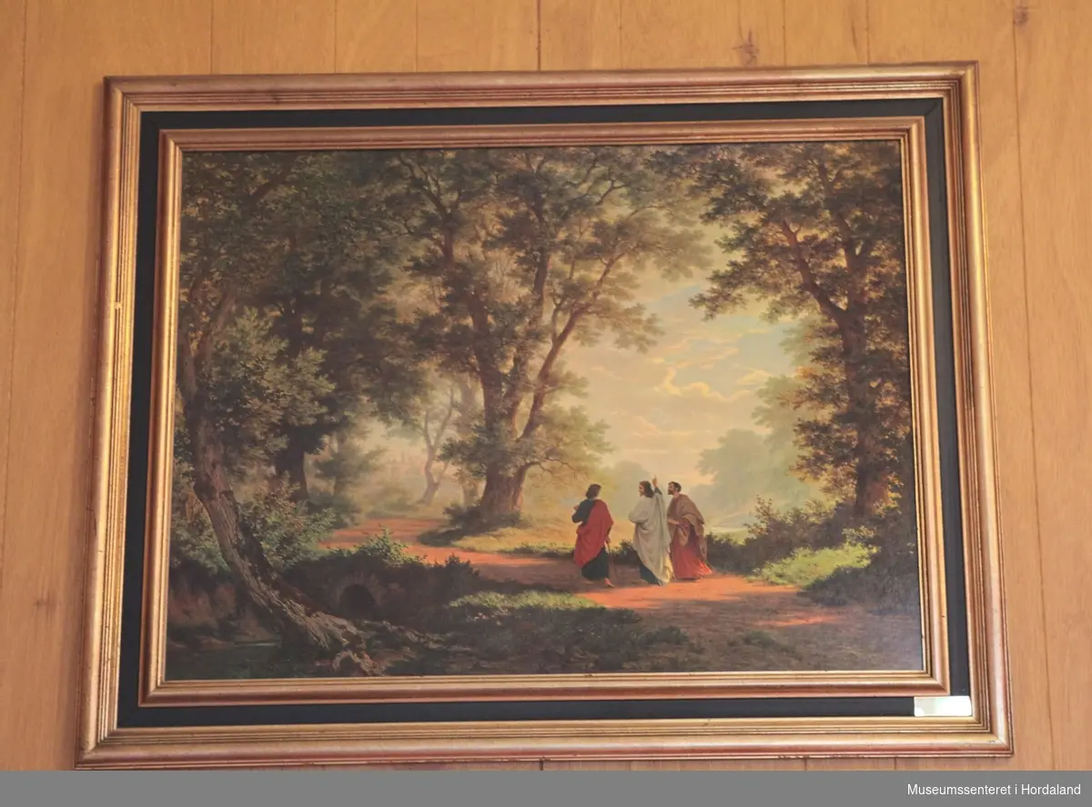 Fargelitografi med forgylt og svart ramme. Bildemotivet viser Jesus i samtale med to disipler i landskap med store trær. De går langs en vei som krysser en liten bru i retning en by plassert langt bak i bakgrunnen.