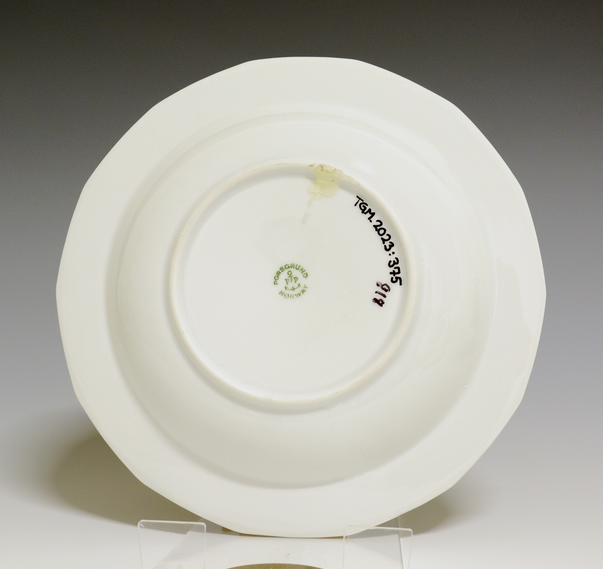 Mangekantet dyp tallerken av porselen med hvit glasur. 
Modell: Octavia, tegnet av Grete Rønning i 1977.
