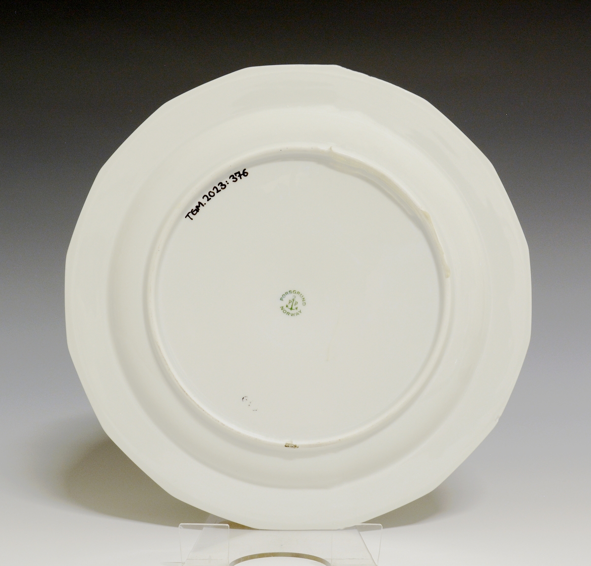 Mangekantet tallerken av porselen med hvit glasur. 
Modell: Octavia, tegnet av Grete Rønning i 1977.