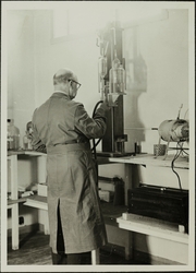 Ein mann i frakk står attmed eit apparat i laboratoriet på S