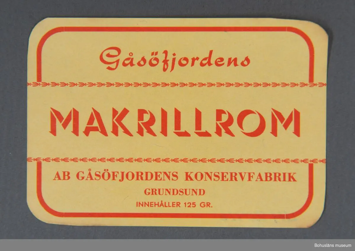Rektangulär etikett med röd text mot gul botten för makrillrom.