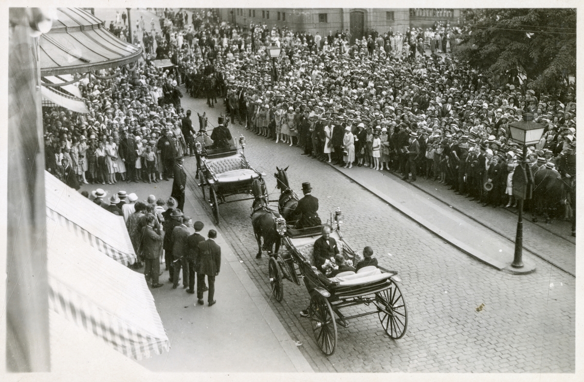 To landauere foran Grand Hotel i Karl Johans gate, omgitt av mange tilskuere. Stortinget i bakgrunnen - Roald Amundsens ankomst til Oslo med S/S "Bergensfjord" efter "Norge"s færden over Polen - 16. juli 1926.