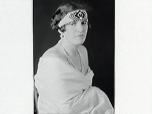 Porträtt av Florence Hansson, iförd ett brett, mönstrat pannband och pärlhalsband.