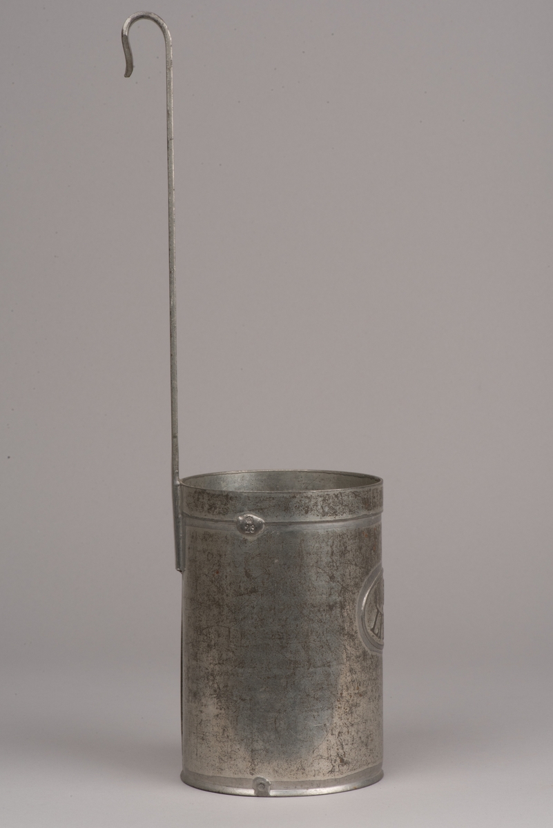 Cylinderformat litermått av plåt.
Handtag i form av ett längre skaft, som avslutas med en böj.
På måttets sida finns en prägling med "1 LITER".