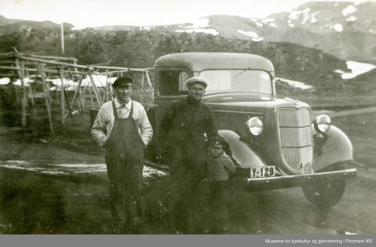Honningsvåg, Storbukt. To menn og en gutt ved en Ford V8 lastebil (årsmodell 1936) med registrering Y-129. Fiskehjeller i bakgrunnen. Omkring 1936.